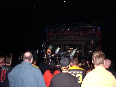1990 Ford Bronco - A crowd of people watches a band perform live on stage, with the band's name prominently displayed on a banner above them.