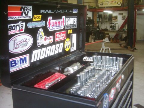 1978 Ford Bronco - A black tool chest is open, displaying rows of sockets and various racing-themed stickers on its lid.