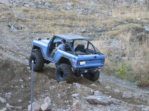 1985 Ford Bronco - Off-road Bronco tackling a challenging rocky hill climb with its large tires.