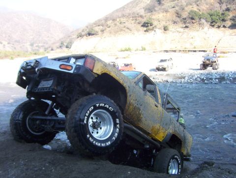 2000 Ford F-450 - Several off-road vehicles navigate a rocky riverbed on a sunny day.