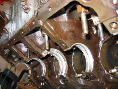 1992 Ford Bronco - Close-up of an engine block's main bearing saddles with the crankshaft removed, showing several main bearing bores, upper bearing shells, a…