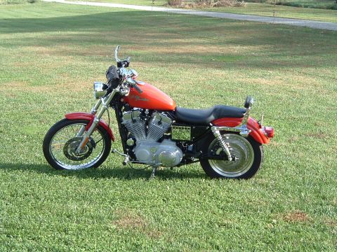 1995 Mercury Grand Marquis - An orange motorcycle with chrome details sits on a grassy field under natural light.