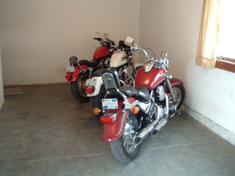 1995 Mercury Grand Marquis - Three motorcycles are parked in a garage. The motorcycles are red and white.