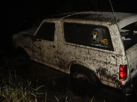 1989 Ford Bronco - A mud-covered 1989 Ford Bronco is stuck in the mud at night.