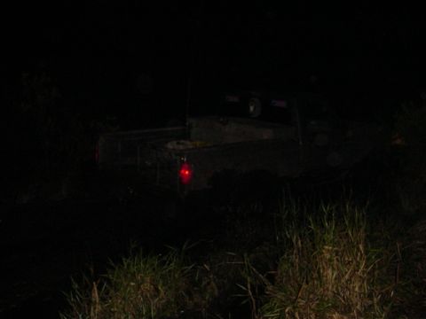 1989 Ford Bronco - Pickup truck is seen from the rear at night, with only its taillight illuminated.