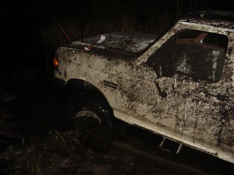 1989 Ford Bronco - Mud-covered 1989 Ford Bronco stuck in a muddy area at night.