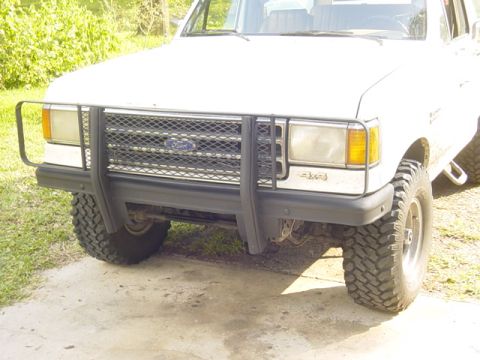 1989 Ford Bronco - The front grille and bumper area of a white Ford truck is visible, a protective bull bar and 4x4 badging.