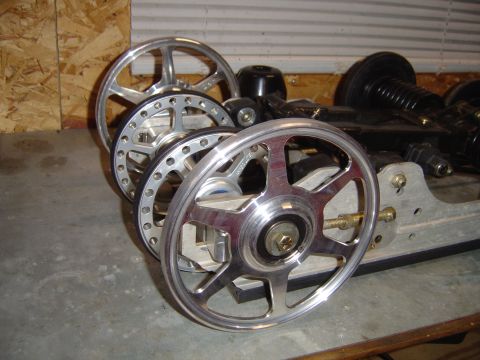 1978 Ford Bronco - Shiny custom wheels and suspension parts are laid out on a concrete floor.
