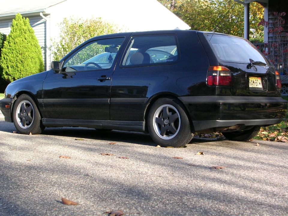 Black Volkswagen Golf Mk3 hatchback, side view, lowered suspension, five-spoke wheels, license plate visible