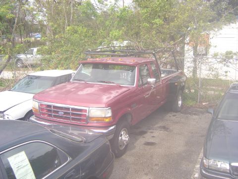 1993 Ford Bronco - This red Ford F-Series truck is equipped with a ladder rack and dual rear wheels.