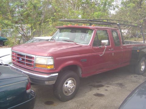 1993 Ford Bronco - This red Ford F-350 dually pickup truck is parked next to other vehicles.
