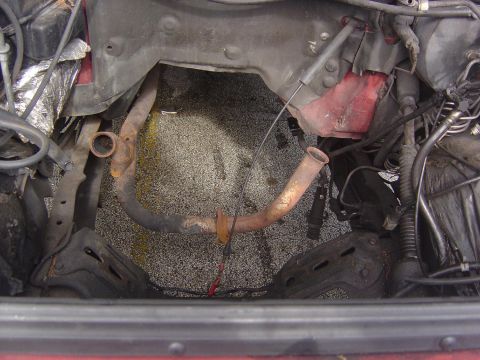 1993 Ford Bronco - The engine bay of a vehicle is shown with exposed exhaust pipes and wiring harnesses.