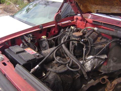 1993 Ford Bronco - The engine bay of a vehicle, showing various mechanical parts and the battery.