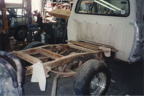 1968 Ford F-100 - Rear three-quarter view of a pickup with the bed removed, exposing the bare rusty ladder frame, rear leaf springs, driveshaft and exhaust b…