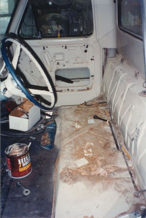 1968 Ford F-100 - Gutted interior of a classic pickup cab mid-restoration, shot from the passenger side: seat removed, bare painted floor pan littered with d…