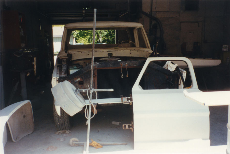 Classic pickup stripped of grille, fenders and doors during disassembly in a garage