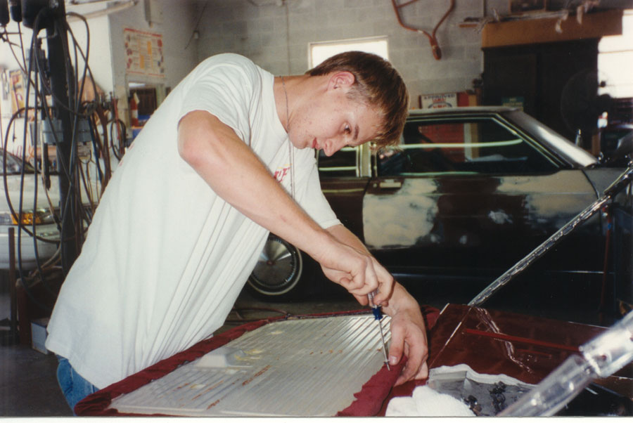 Man working with a screwdriver on a ribbed aluminum door panel in a garage shop