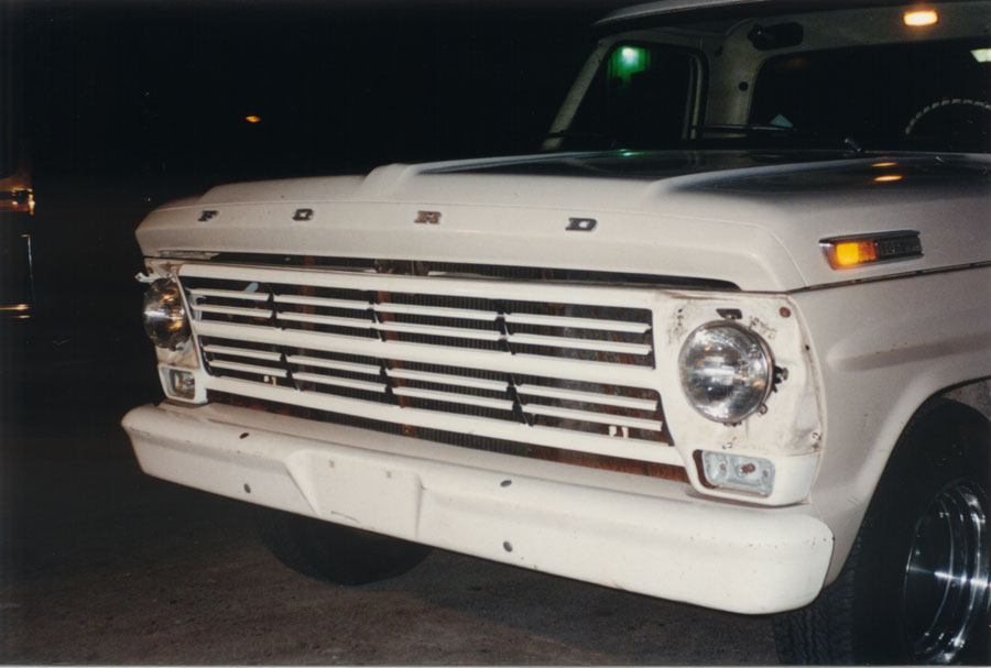 Night front-corner view of white classic Ford pickup with FORD hood lettering