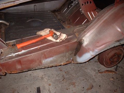 1971 Ford Torino - The interior of a vehicle shows significant rust damage on the floor pan and rocker panel, with tools laid out.
