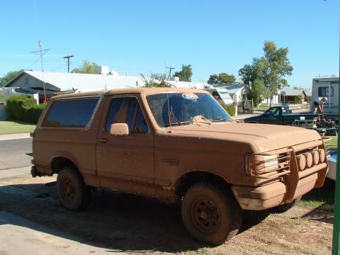 1990 Ford Bronco - This 1990 Ford Bronco is heavily covered in mud, suggesting recent off-road use.