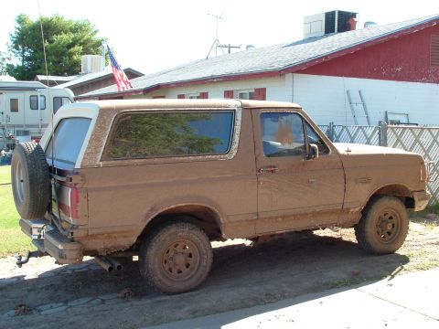 1990 Ford Bronco - This 1990 Ford Bronco is heavily covered in mud, suggesting recent off-road activity.