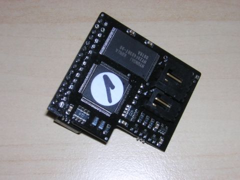 1998 Ford Crown Victoria - small black electronic tuning module circuit board bearing chips, headers and a logo sticker, on a wood surface.