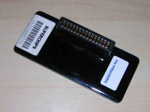 1998 Ford Crown Victoria - black Superchips tuning module with a barcode label and gold card-edge connector, lying on a light wood surface.