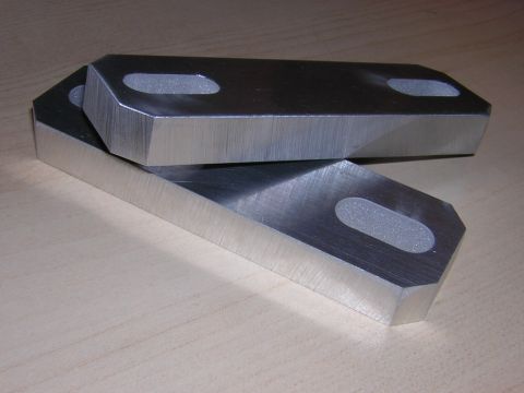 1998 Ford Crown Victoria - pair of thick brushed-aluminum spacer blocks with oval slotted holes, stacked on a light wood surface.