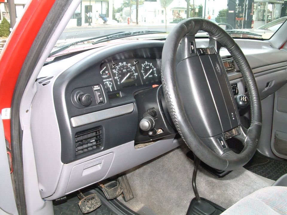Ford truck dashboard with analog gauges, steering wheel and H-pattern manual shifter knob