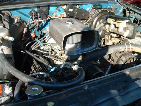 1994 Ford Bronco - The engine bay shows an aftermarket air intake system and various engine parts.