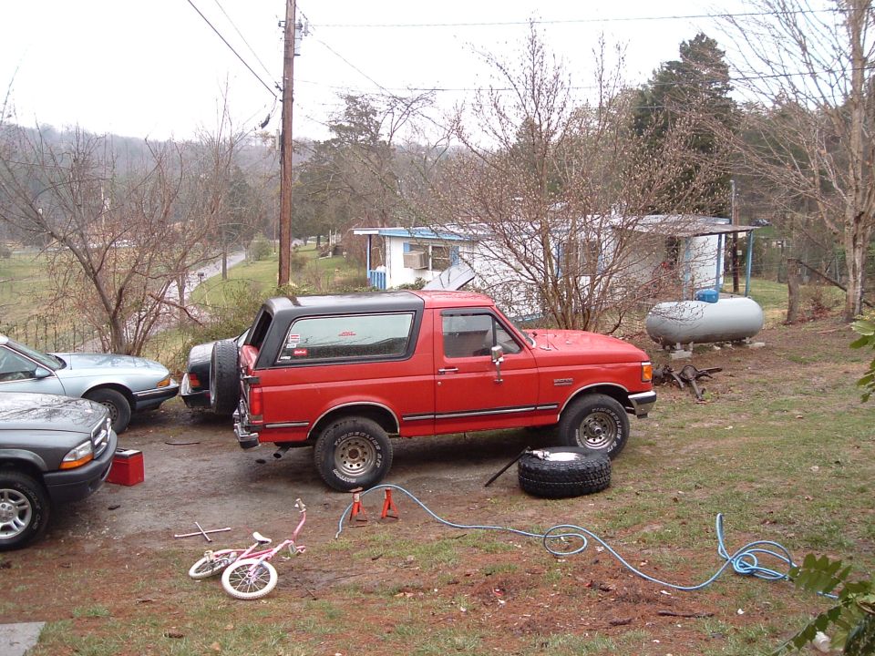 Red 1987 Ford Bronco with black top, spare tire mounted on rear door