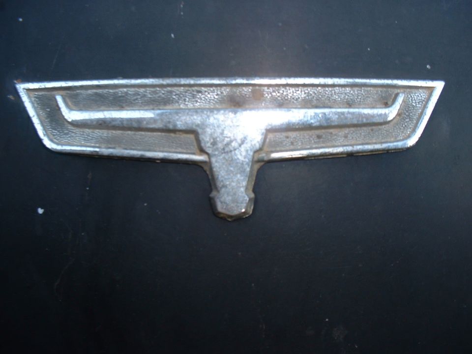 Chrome emblem with a horizontal bar and a T-shaped element below