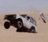 1967 Ford Bronco - A white off-road vehicle navigates a sandy terrain with one wheel lifted.