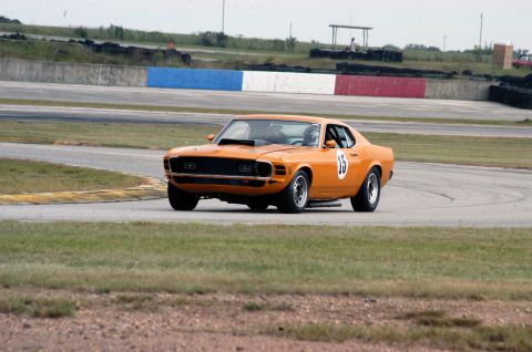 1970 Ford Mustang - A vintage orange Ford Mustang races around a track, displaying the number 15 on its side.