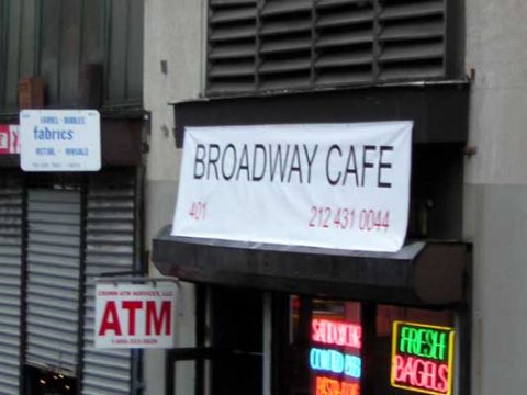 1995 Ford Bronco - A sign for Broadway Cafe displays its address and phone number, with a smaller sign for fabrics nearby.