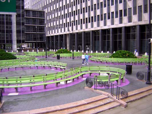 Urban plaza with curved green benches and purple accents, leading to a modern building