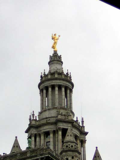 1995 Ford Bronco - A building's ornate spire is crowned by a golden statue, under an overcast sky.