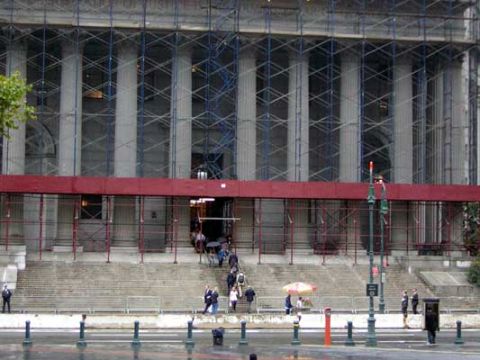 1995 Ford Bronco - A large building is under construction with scaffolding covering its facade and many people walking up the steps.