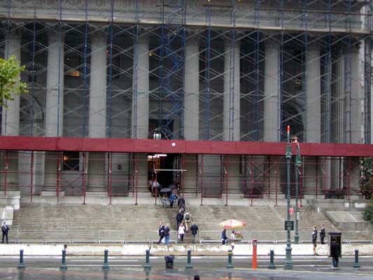 Building with scaffolding, red awning, and people on wide steps