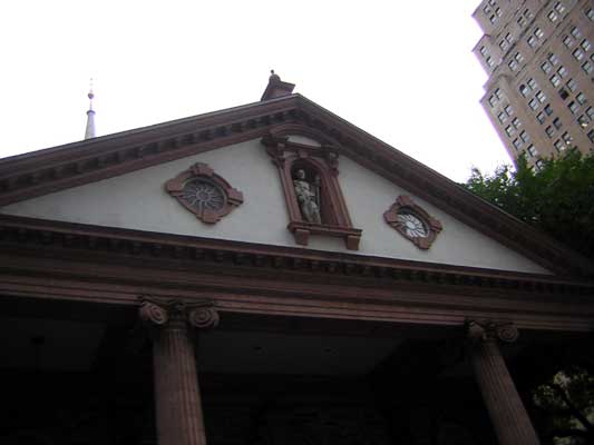 building facade with columns, decorative windows, and a statue in a niche