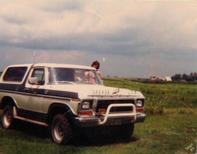 White and green 1978 Ford Bronco with 'GREASE JOB' on hood, parked in a field, Sept 1981 photo