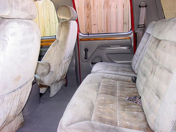 Interior view of a van with plush cloth seats and wood trim