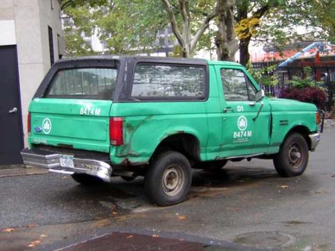 1995 Ford Bronco - Green Ford Bronco seen from the rear, showing its distinctive body style and markings.