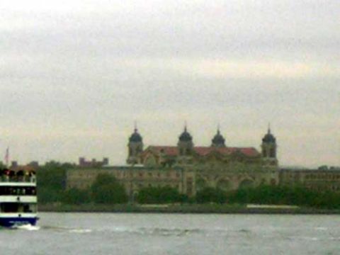 1995 Ford Bronco - A ferry boat travels on the water in front of a large, ornate building under a cloudy sky.