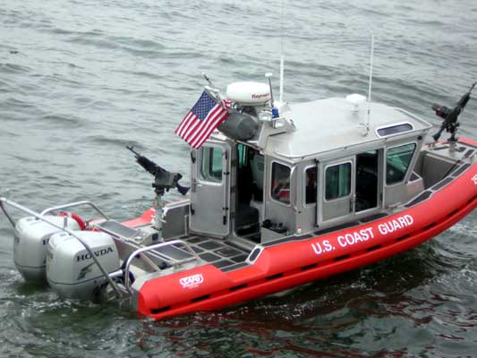 Red U.S. Coast Guard boat with two outboard motors and mounted guns