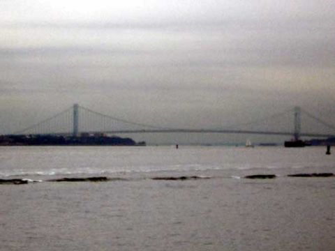 1995 Ford Bronco - A long suspension bridge spans across a body of water under an overcast sky.