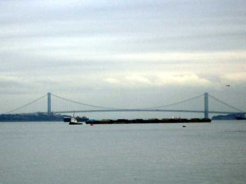 1995 Ford Bronco - A tugboat navigates near barges with the Verrazzano-Narrows Bridge in the background on an overcast day.