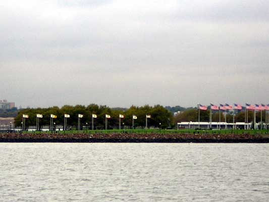 Waterfront with a line of flags and buildings in the background under a cloudy sky