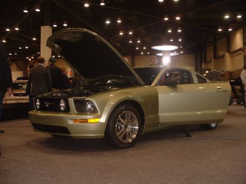 1999 Ford Crown Victoria - Light green Ford Mustang on display at an auto show, hood open to reveal the engine.