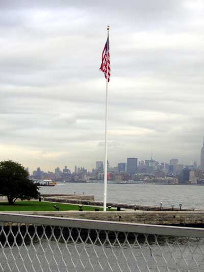 1995 Ford Bronco - An American flag flies high against a cloudy sky, with the New York City skyline visible across the water.